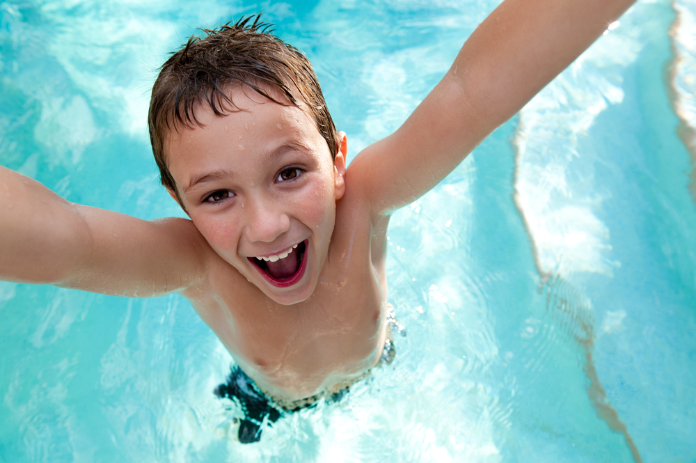 young boy smiling in swimming pool